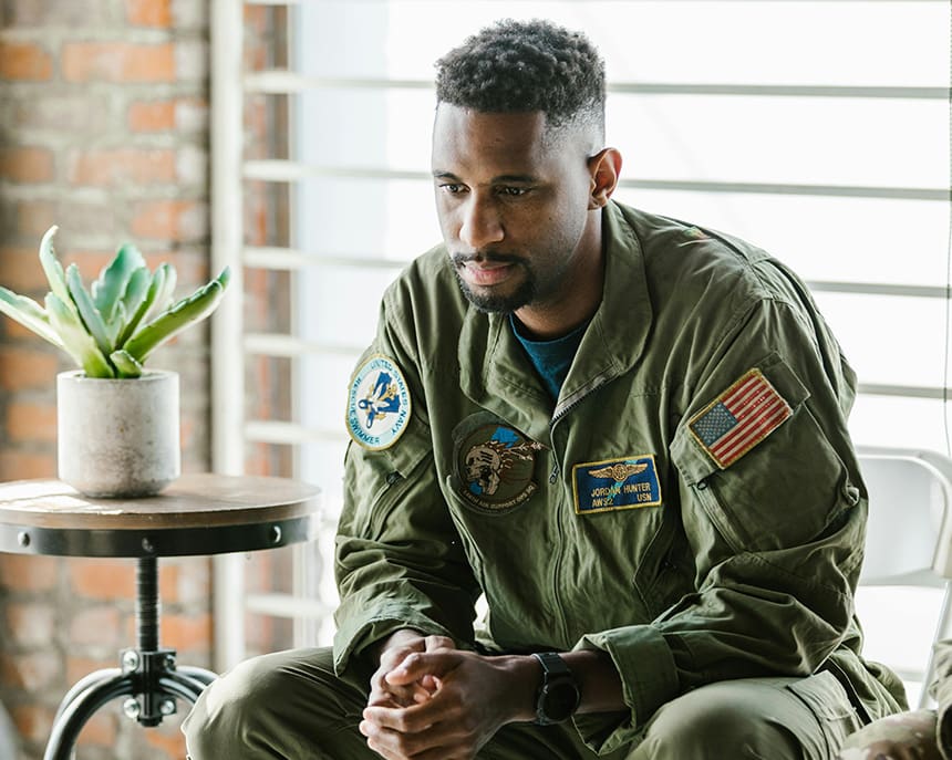 A man in military fatigues sitting on the ground.