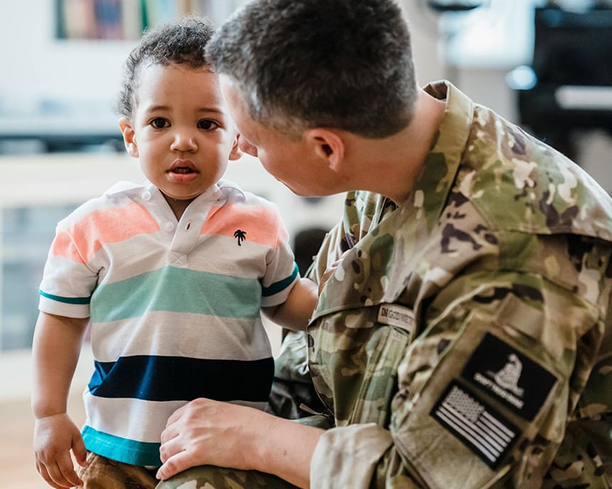 A man in military fatigues holding a child.